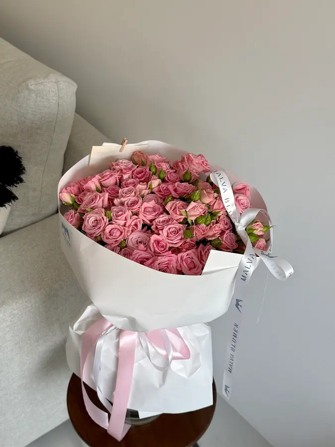 Rosa Rosenstrauß mit Schleife auf einem Beistelltisch