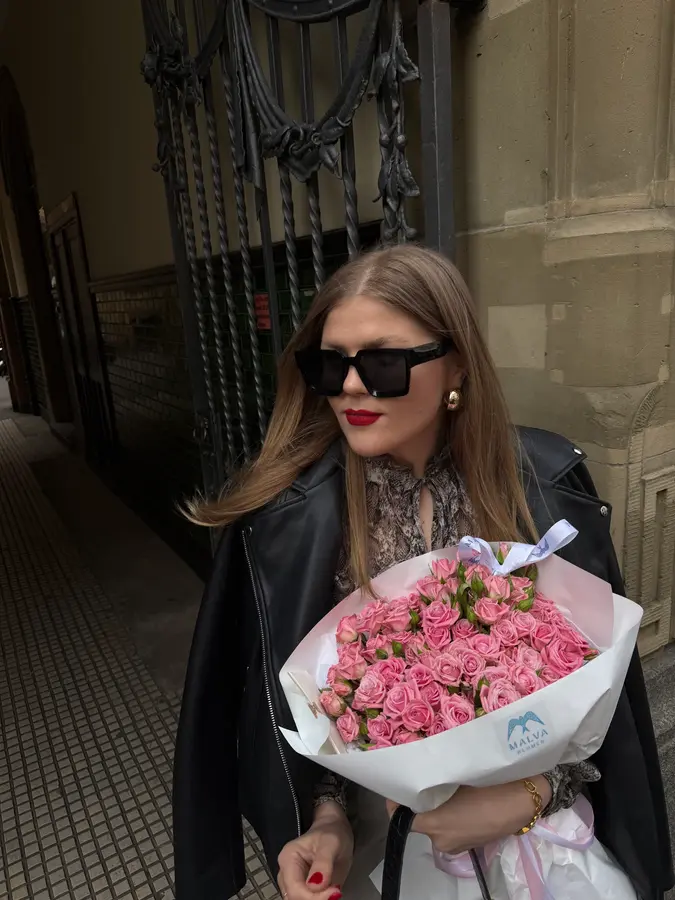 Frau in Lederjacke mit großem rosa Rosenstrauß vor einem Stuttgarter Altbau