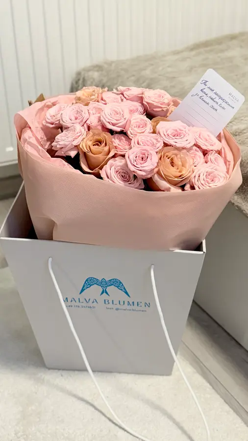 Rosa und apricotfarbene Rosen in einer weißen Tragetasche mit dem blauen Malva-Vogel